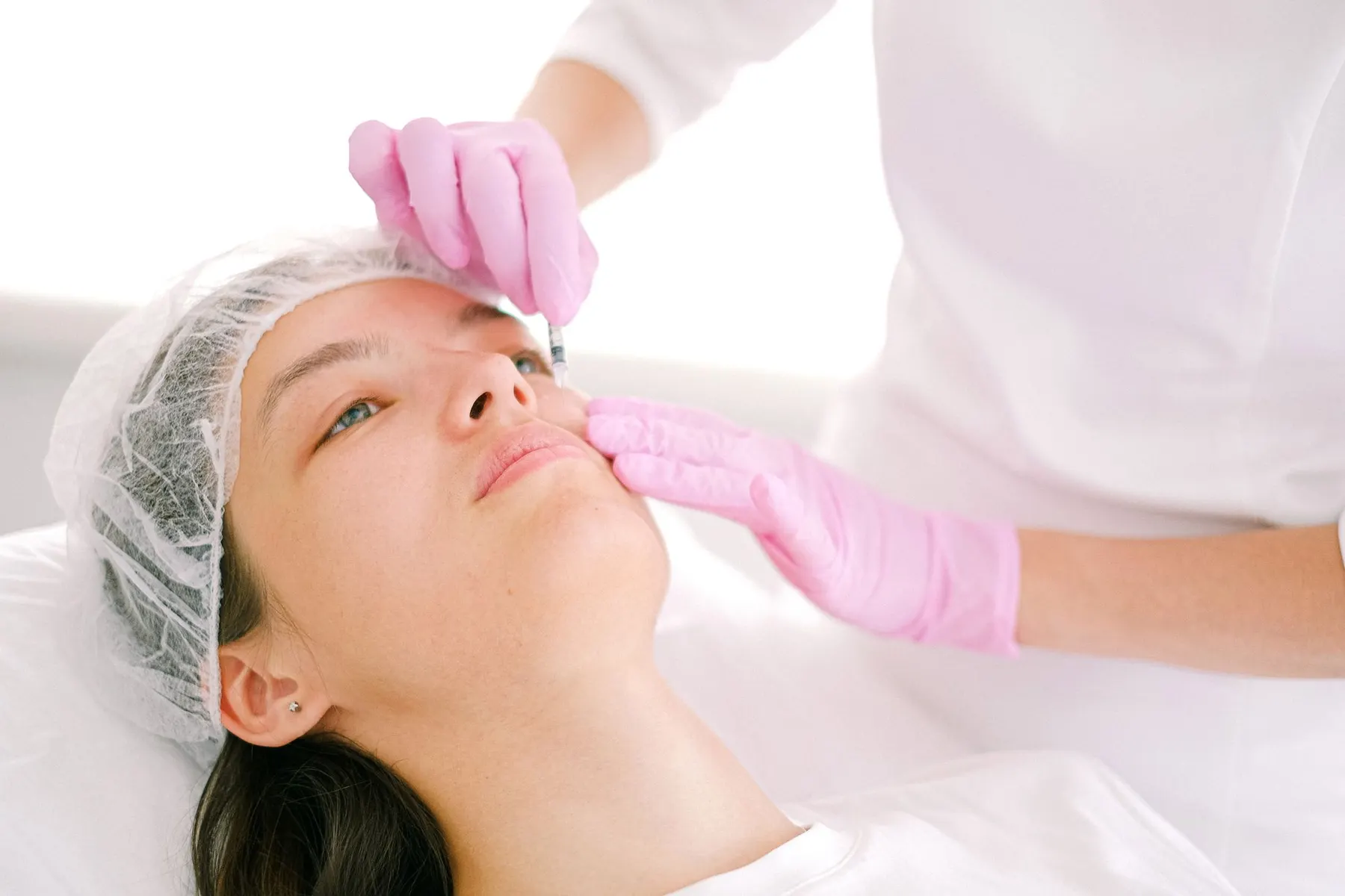 A patient receiving a cosmetic treatment in a bright, calm clinical setting