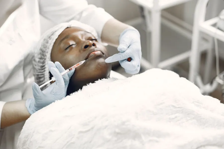 A woman receiving a cosmetic injection in a bright clinical setting