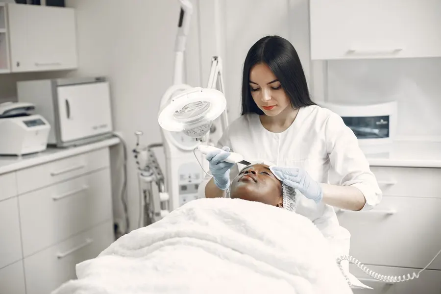 An aesthetician providing a facial treatment to a client in a modern clinic